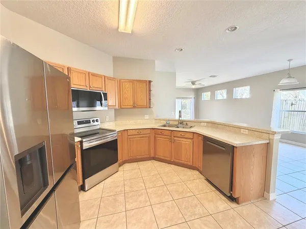 a kitchen with stainless steel appliances granite countertop a stove top oven a sink dishwasher a refrigerator and a microwave