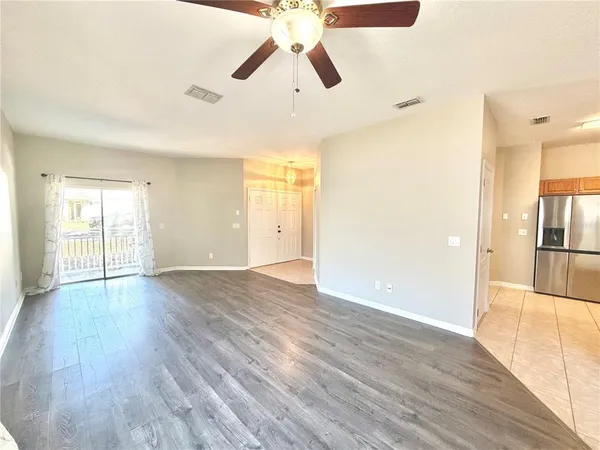 a view of empty room with wooden floor and fan