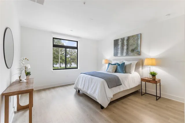 a bedroom with a bed a painting and a window