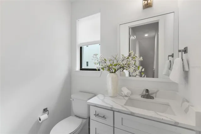 a bathroom with a granite countertop sink a toilet and mirror