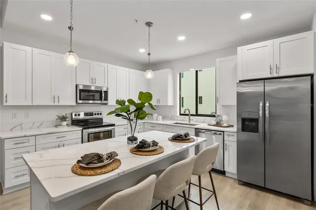 a kitchen with a refrigerator a stove a dining table and chairs with wooden floor