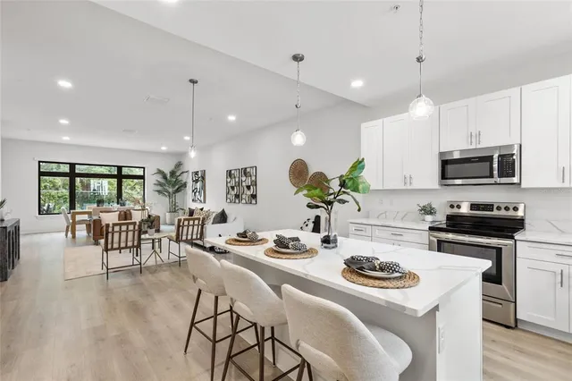 a kitchen with stainless steel appliances kitchen island granite countertop a stove a sink a dining table and chairs with wooden floor