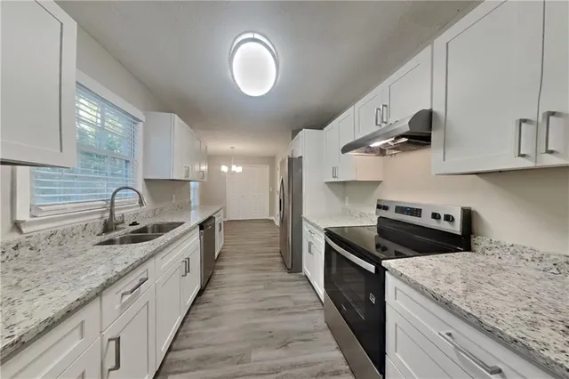 a kitchen with stainless steel appliances granite countertop a sink a stove and a wooden cabinets