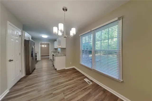 a view of a hallway with wooden floor and a kitchen