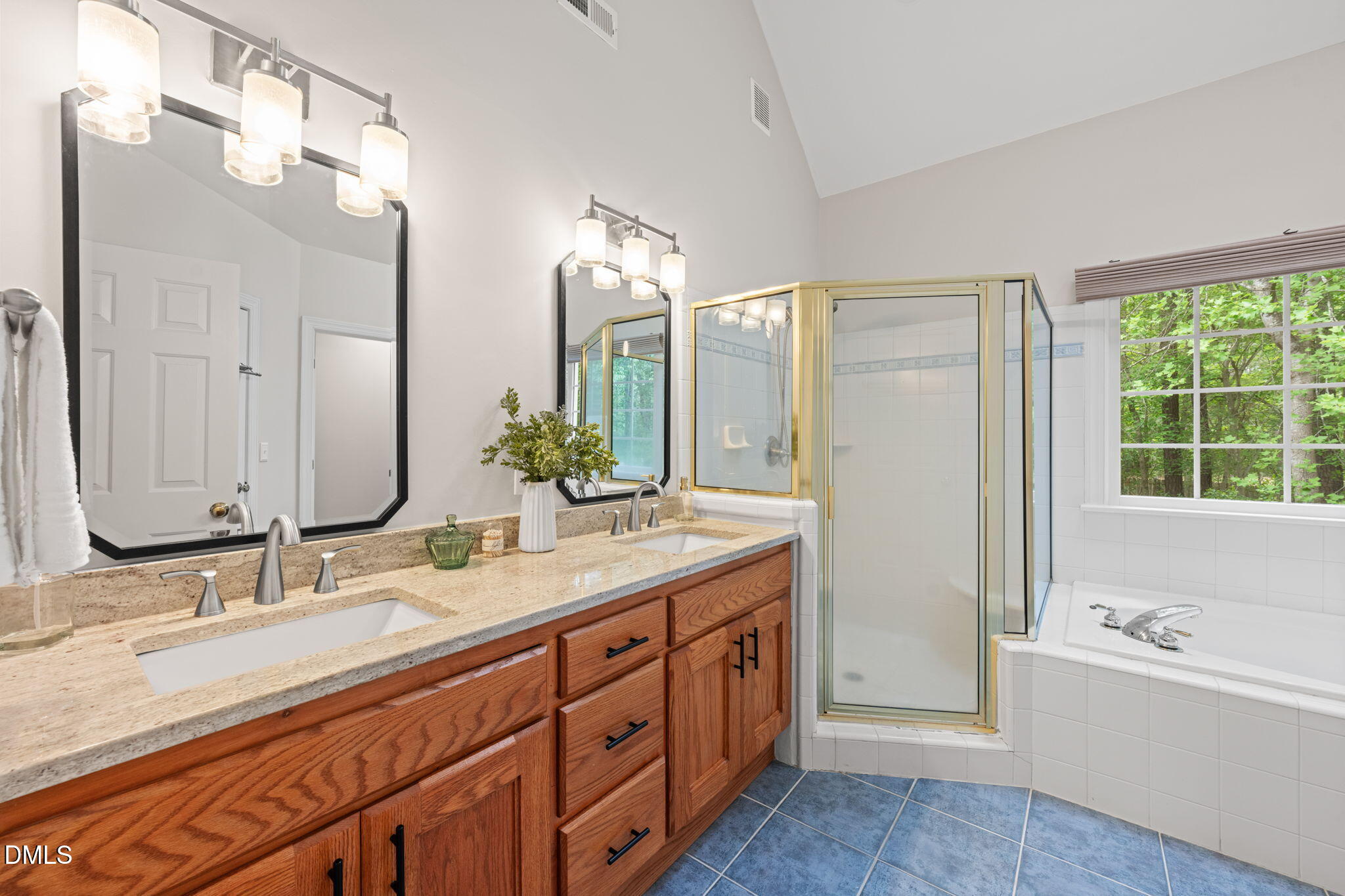 5809 Stone Spring Road Raleigh, NC 27613 - Photo 24 of 54 a bathroom with a double vanity sink a large mirror a bathtub and next to a window