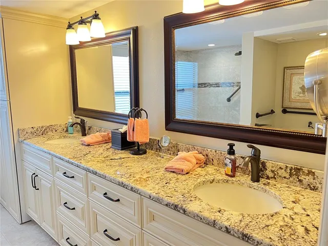 a bathroom with a granite countertop double vanity sink and a mirror