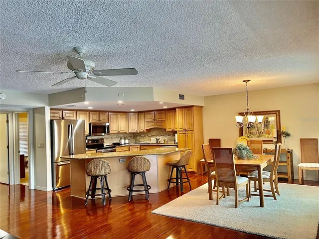 a kitchen with stainless steel appliances a dining table chairs stove and wooden floor