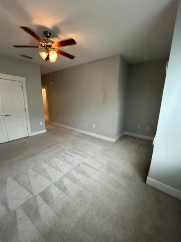 a view of an empty room with a chandelier fan