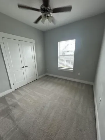 en empty room with windows and ceiling fan