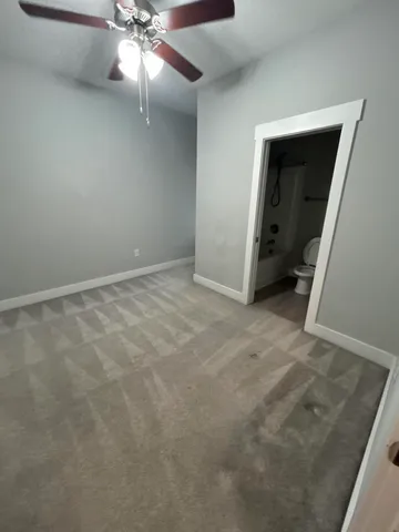 an empty room with a ceiling fan and a rug