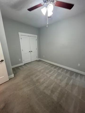 an empty room with a chandelier fan and a large window