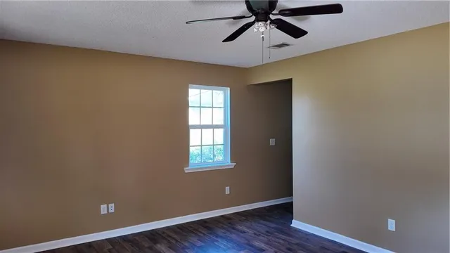 an empty room with windows and fan