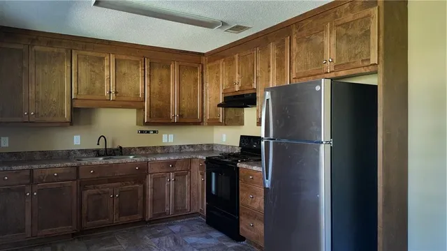 a kitchen with stainless steel appliances granite countertop a refrigerator and a sink