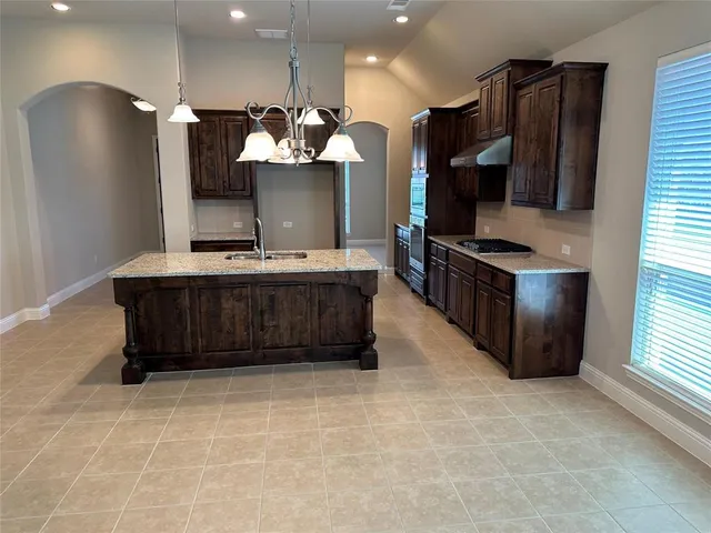 a kitchen with stainless steel appliances granite countertop a stove a sink and a refrigerator