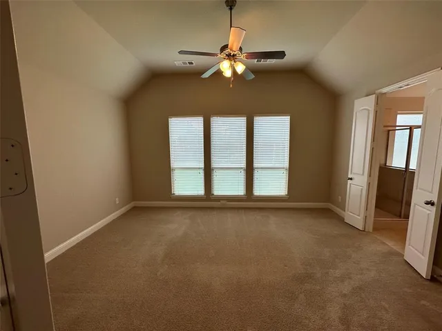 an empty room with chandelier fan and windows