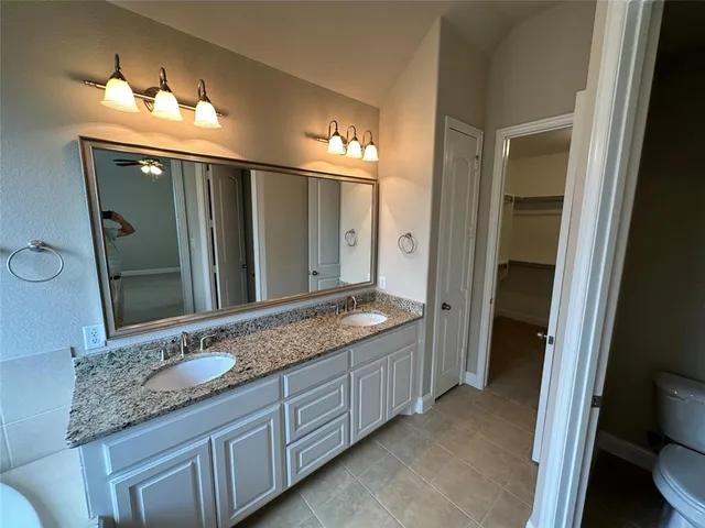 a bathroom with a granite countertop double vanity sink and a mirror