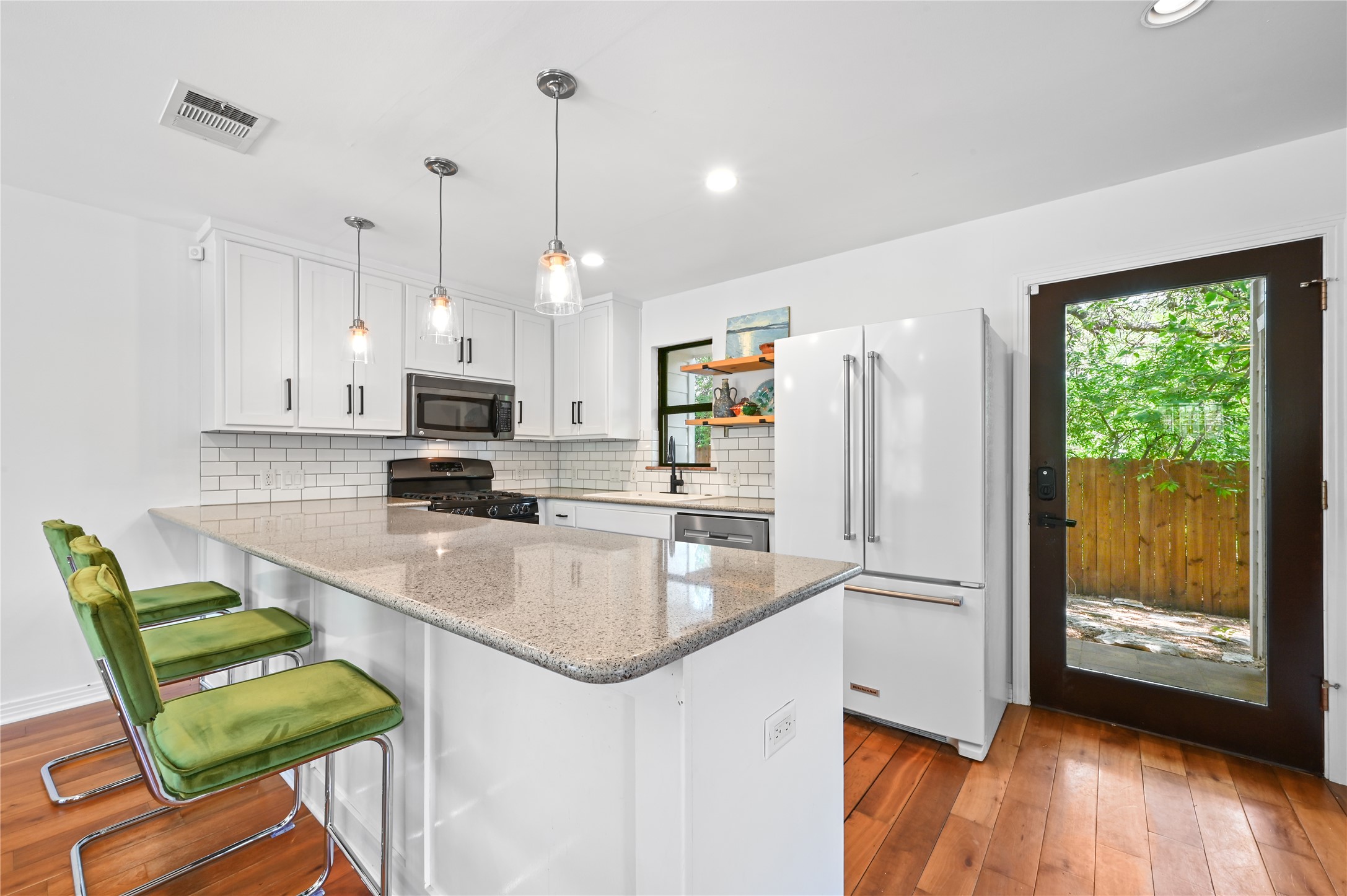 2107 East 13th Street Austin, TX 78702 - Photo 7 of 25 a kitchen with stainless steel appliances granite countertop a sink a stove a refrigerator a microwave oven with a dining table and chairs