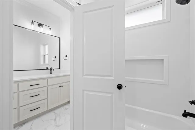 a bathroom with a bathtub a sink a vanity a lamp and a window