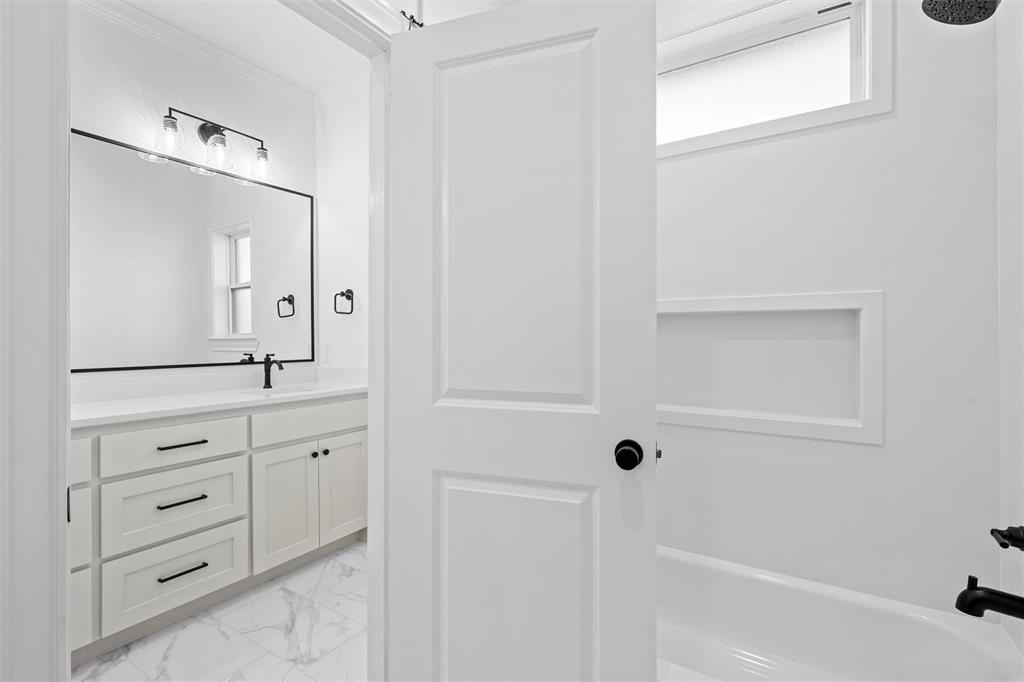 2113 Holborn Street Lorena, TX 76655 - Photo 18 of 31 a bathroom with a bathtub a sink a vanity a lamp and a window