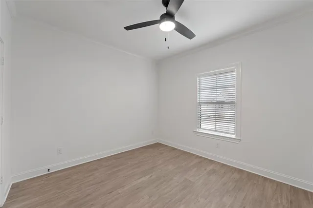 an empty room with wooden floor chandelier fan and windows