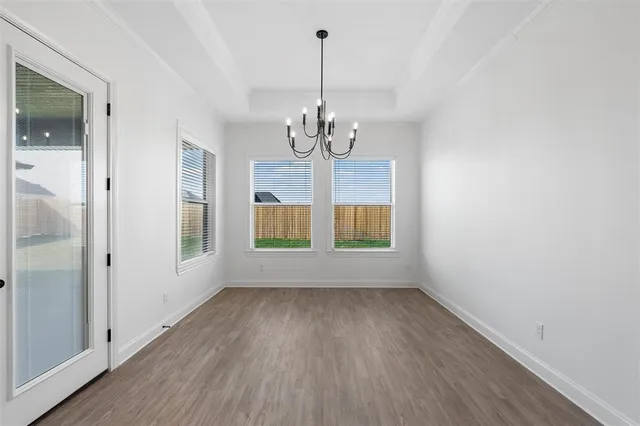 a view of a room with wooden floor chandelier and windows