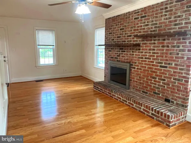 a view of an empty room with wooden floor and a fireplace