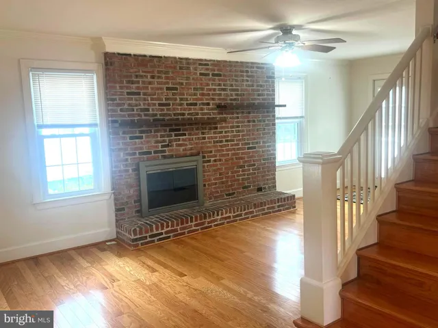 a view of an empty room with wooden floor fireplace and a window