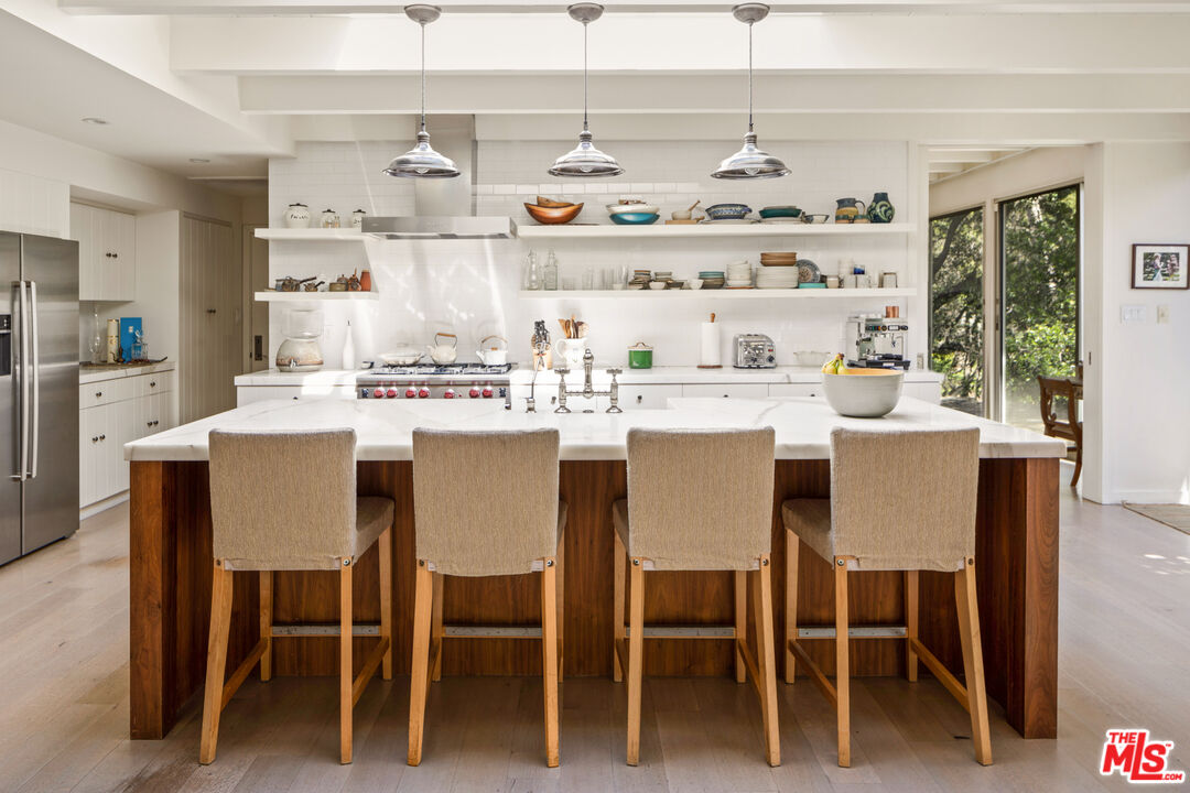 830 Brooktree Road Pacific Palisades, CA 90272 - Photo 13 of 37 a dining room with stainless steel appliances a table and chairs
