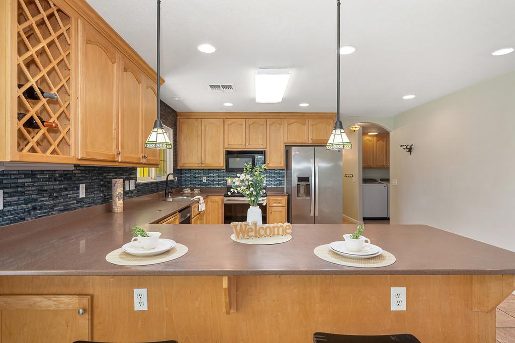 6181 Lambert Lane El Dorado, CA 95623 - Photo 25 of 68 kitchen with hanging light fixtures, arched walkways, stainless steel appliances, and a peninsula