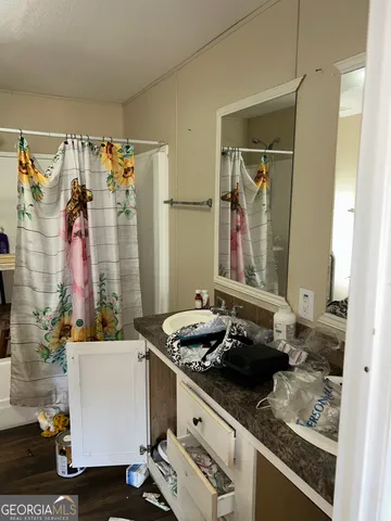 a bathroom with a granite countertop sink a mirror and shower