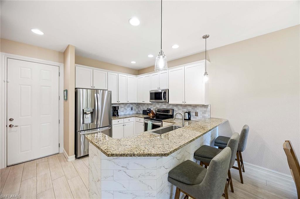 9076 Rialto Street, Unit 62 Naples, FL 34113 - Photo 13 of 50 a kitchen with stainless steel appliances granite countertop a refrigerator a stove a sink dishwasher a dining table and chairs with wooden floor