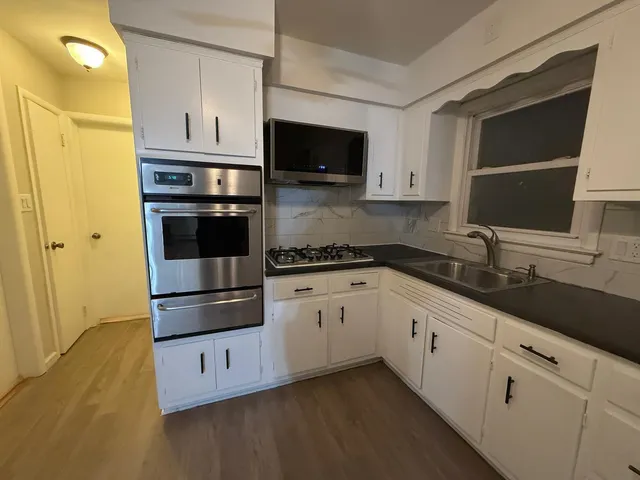 a kitchen with granite countertop white cabinets and stainless steel appliances