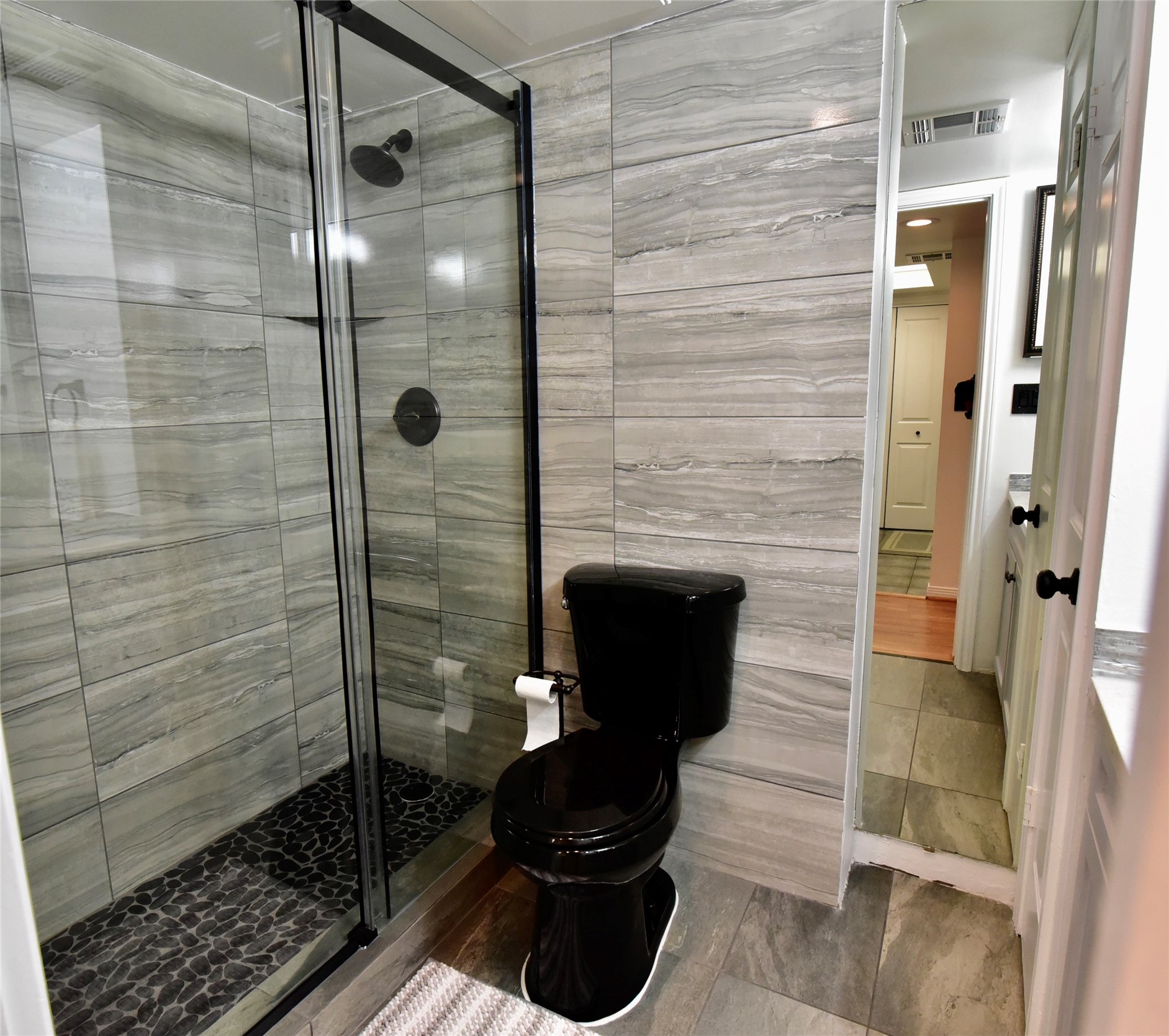 3525 Sage Road, Unit 701 Houston, TX 77056 - Photo 22 of 48 Renovated bathroom featuring glass-enclosed shower with tile and pebble accents.