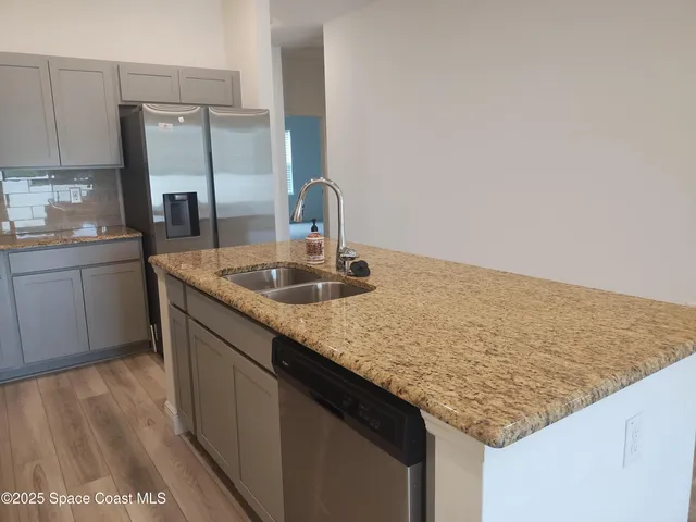 a kitchen with granite countertop sink and refrigerator