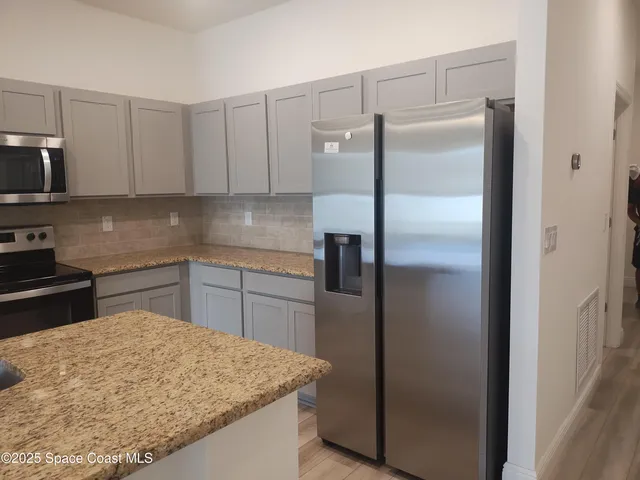 a kitchen with stainless steel appliances granite countertop a refrigerator and a sink