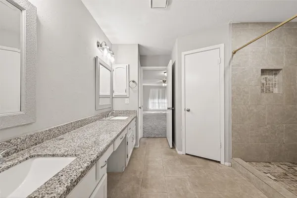 a bathroom with a granite countertop tub sink and mirror