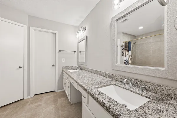 a bathroom with a granite countertop double vanity sink mirror and double