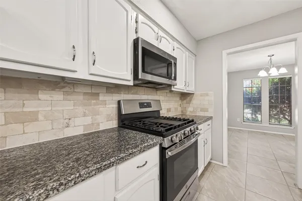 a kitchen with granite countertop white cabinets stainless steel appliances and a sink