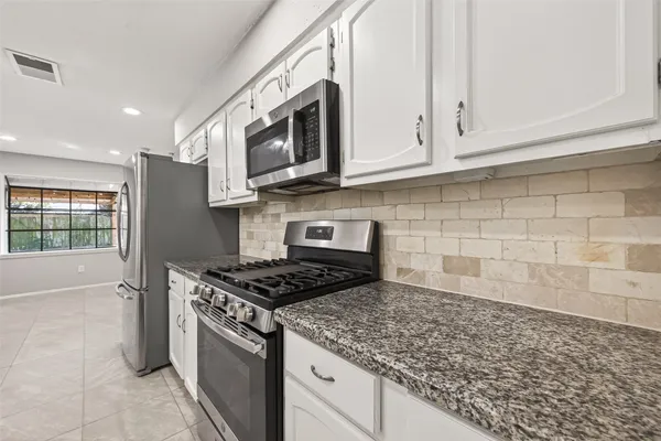a kitchen with stainless steel appliances granite countertop a sink stove and microwave