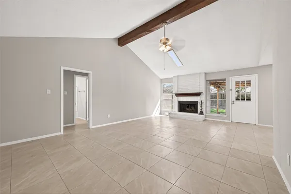 a view of a livingroom with a fireplace a ceiling fan and windows