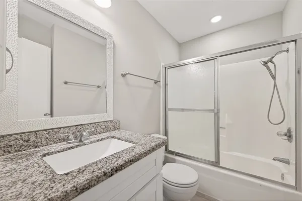 a bathroom with a granite countertop sink toilet and shower