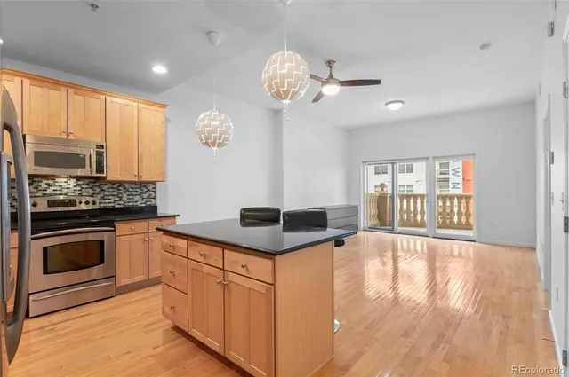 a kitchen with stainless steel appliances granite countertop a stove a sink dishwasher and a fireplace with wooden floor