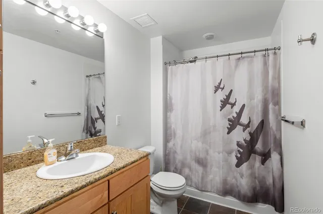 a bathroom with a granite countertop sink toilet and shower