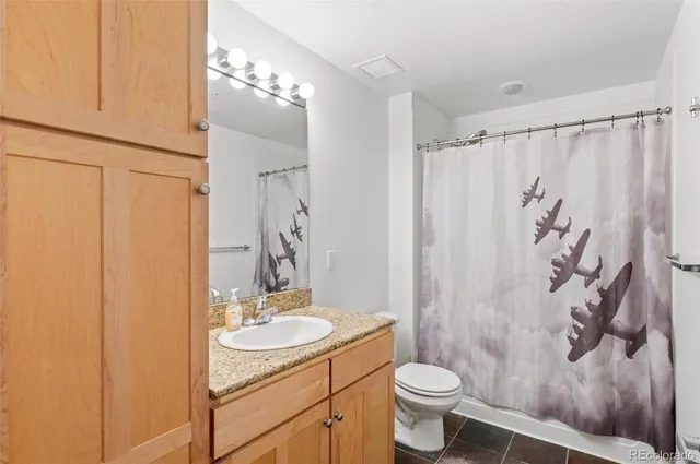a bathroom with a granite countertop sink toilet and shower