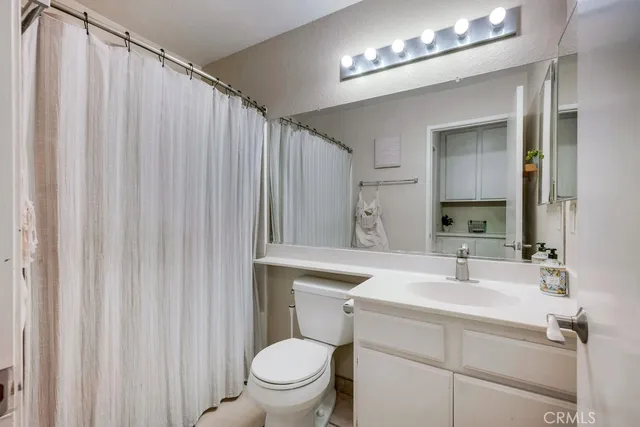 a bathroom with a sink a toilet a mirror and shower curtain