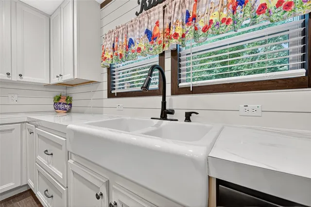 a kitchen with white cabinets and window
