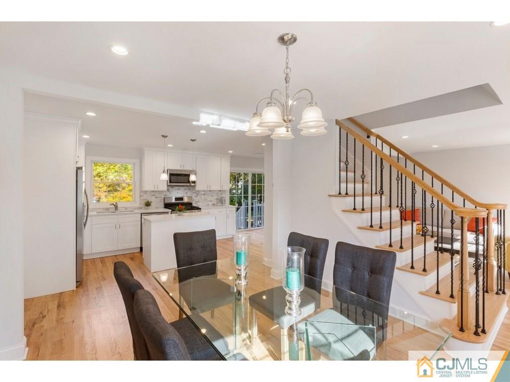 80 Lancaster Road Colonia, NJ 07067 - Photo 3 of 15 a view of a dining room and livingroom with furniture wooden floor a rug a painting and a chandelier