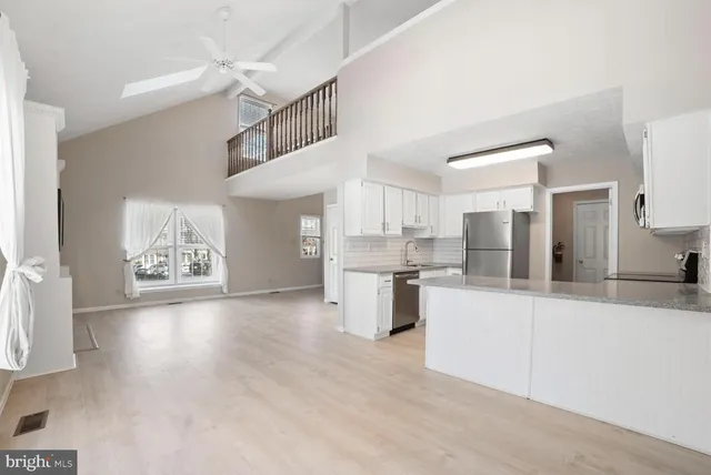 a large white kitchen with cabinets a sink and appliances