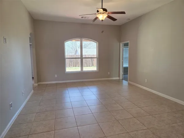 an empty room with windows and chandelier fan