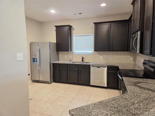 a kitchen with stainless steel appliances granite countertop a refrigerator and a sink